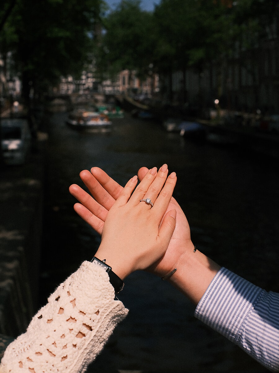 Engagement SP10 Storytelling close-up of a couple's hands meeting palm to palm with the diamond ring above an Amsterdam canal