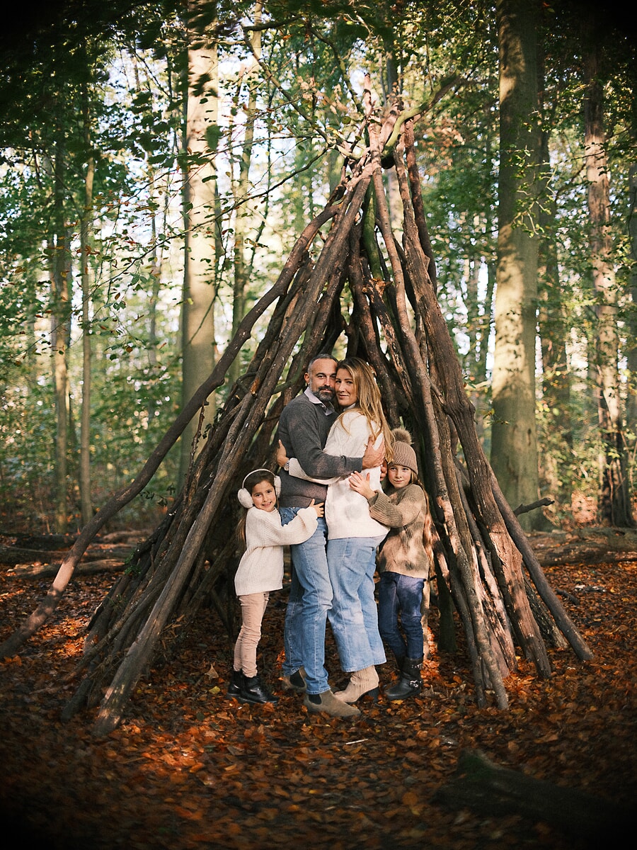 Family SP14 Parents and their two children embracing inside a teepee of branches, an autumn woodland scene of family photography