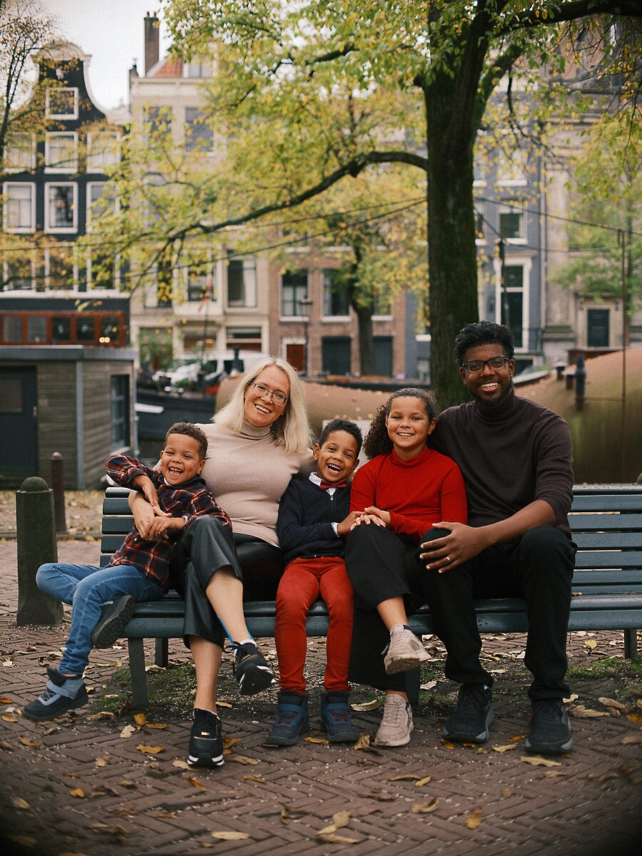 Family SP3 Multigenerational family laughing together on a canal bench in autumn, a grandmother surrounded by her grandchildren during their family photography session
