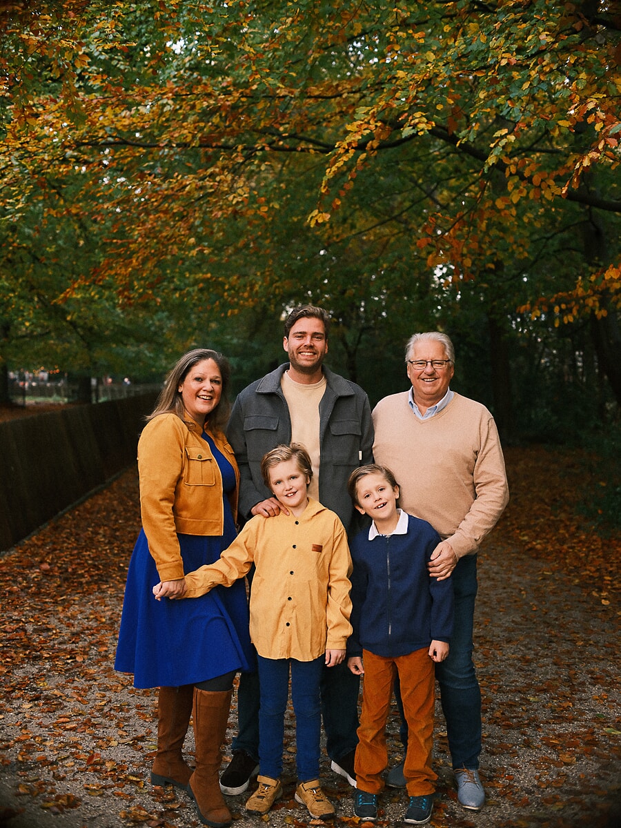 Family SP6 Three generations on a leaf-strewn forest path in autumn, a grandfather joining the parents and two boys for their family portraits