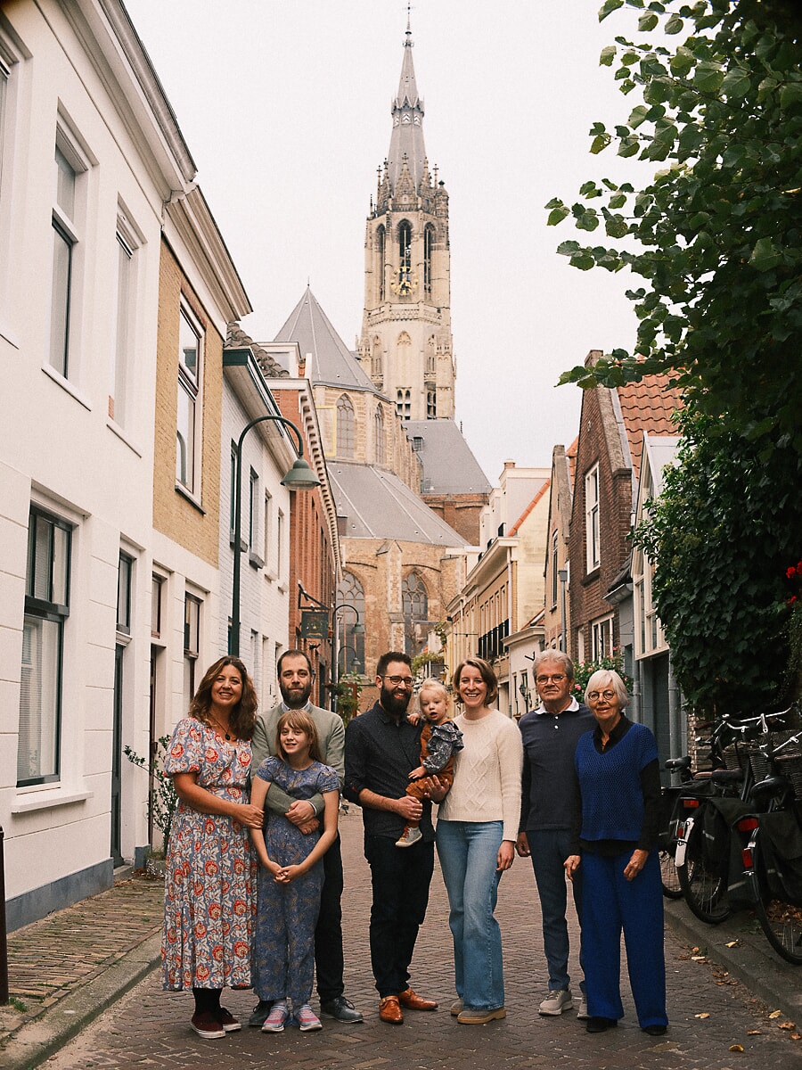 Group Family SP11 Extended family reunion photoshoot in a cobbled street, a tall church tower rising behind them in autumn light