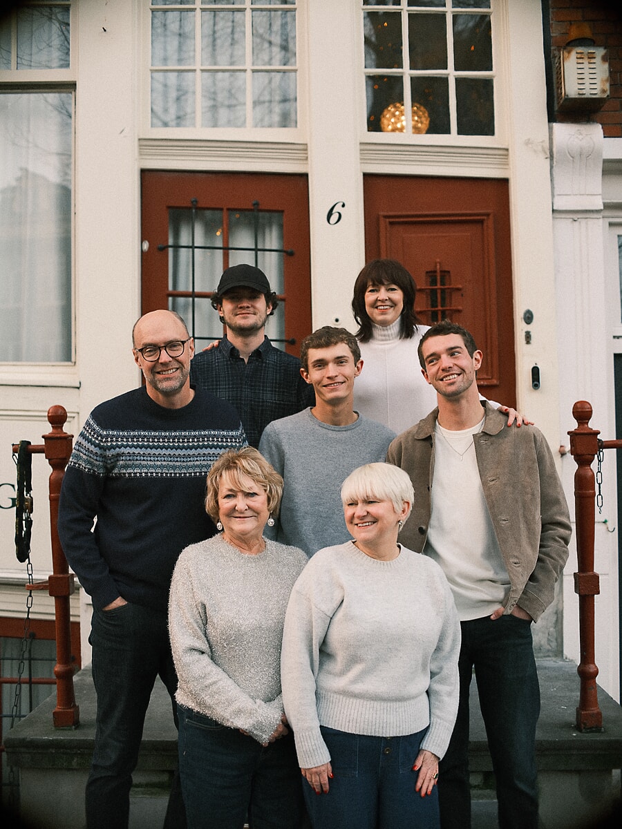Group Family SP6 Three generations on the steps of an Amsterdam townhouse for a wedding anniversary session, grandmothers seated in front of their children and grandchildren
