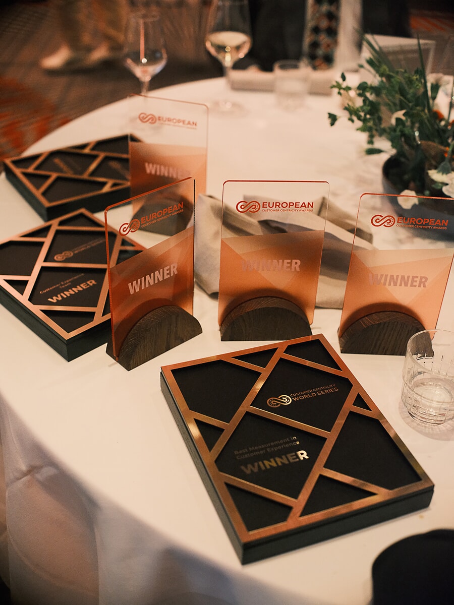 Award trophies laid out on a white table, acrylic winner plaques beside a framed copper award