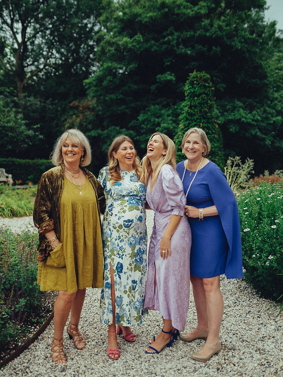 Group Family SP13 Three generations of women laughing together in a green garden, grandmother, mother and daughters sharing a joyful moment during their family portraits