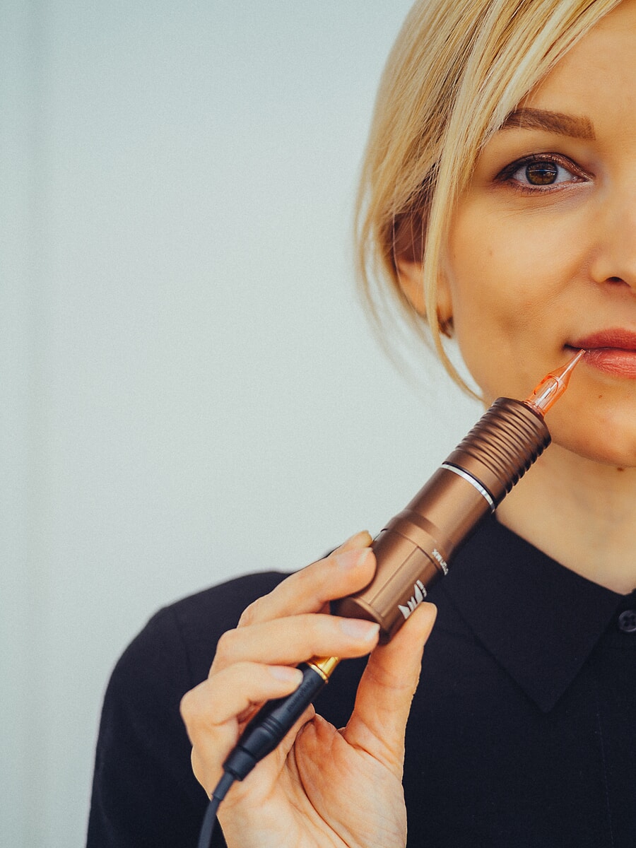 Close crop of a woman holding a permanent makeup pen up beside her lips