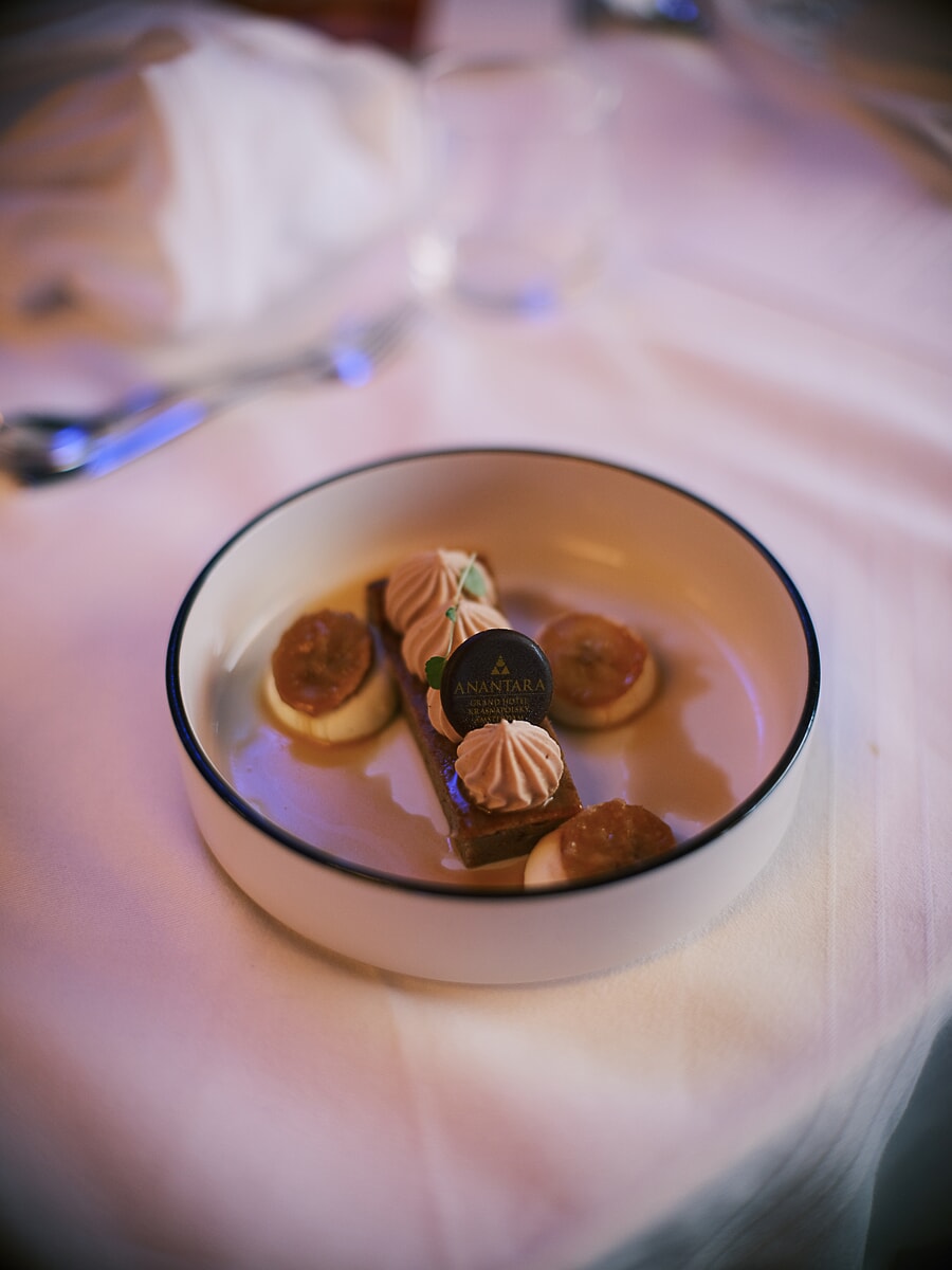 Plated dessert finished with a chocolate medallion, photographed on pale linen