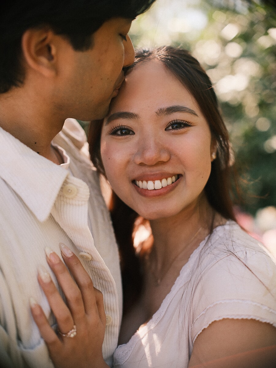 Newly engaged woman beaming as her partner kisses her forehead during an Amsterdam proposal photoshoot