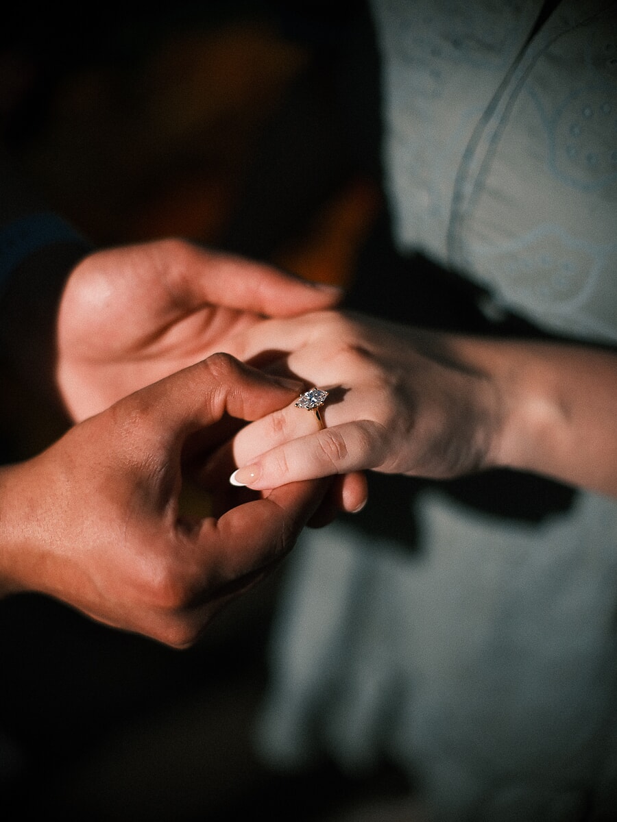Close-up of the engagement ring sliding onto her finger in the last light of a surprise proposal