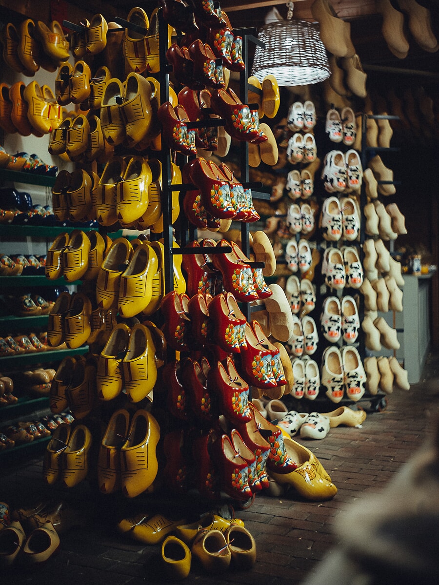 Racks of painted wooden clogs filling a shop wall, yellow, red floral and cow-print pairs side by side