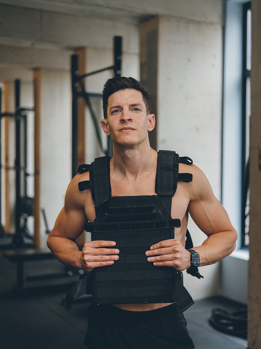 Trainer in a weighted training vest with both hands on the plate, looking straight to camera, a portrait from a branding photoshoot in Amsterdam