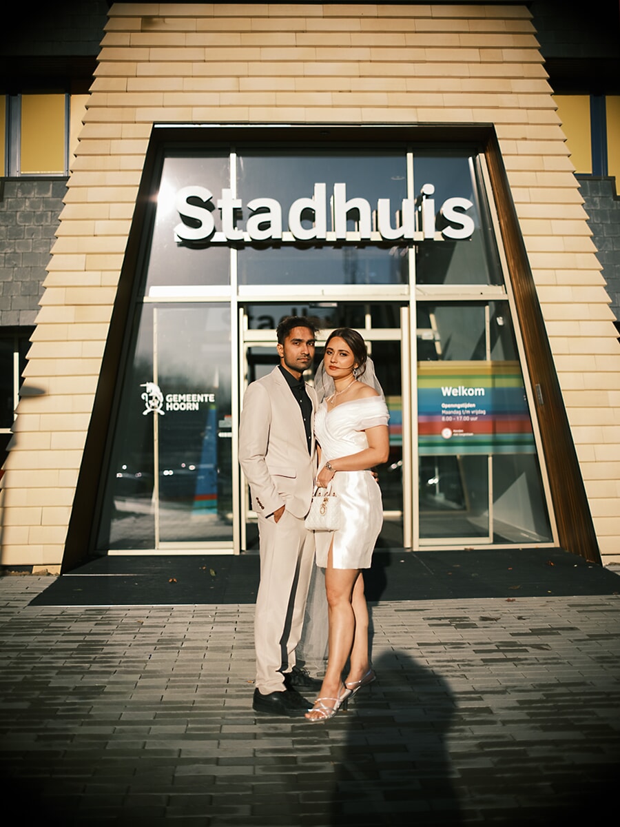 Wedding Ceremony SP1 Bride and groom hand in hand before an Amsterdam Stadhuis city hall entrance in golden evening light, captured by a wedding photographer in Amsterdam