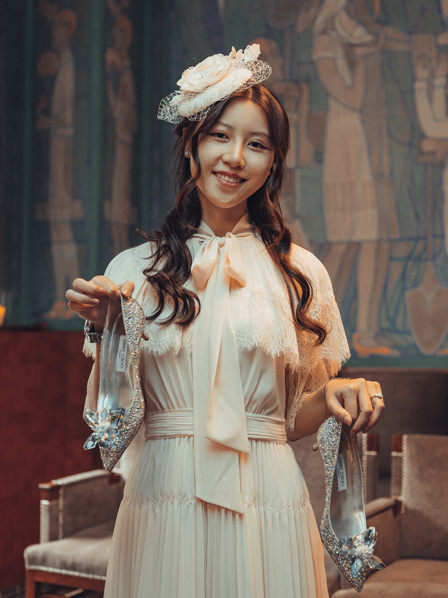 Wedding Ceremony SP11 Elegant bridal portrait of a woman in a blush vintage gown and fascinator holding crystal heels in a tapestried hall