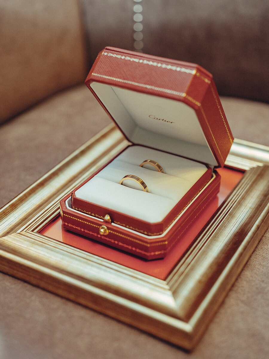Wedding Ceremony SP12 Two wedding bands in a red Cartier box resting on a gilded frame, a refined detail from the wedding photo session