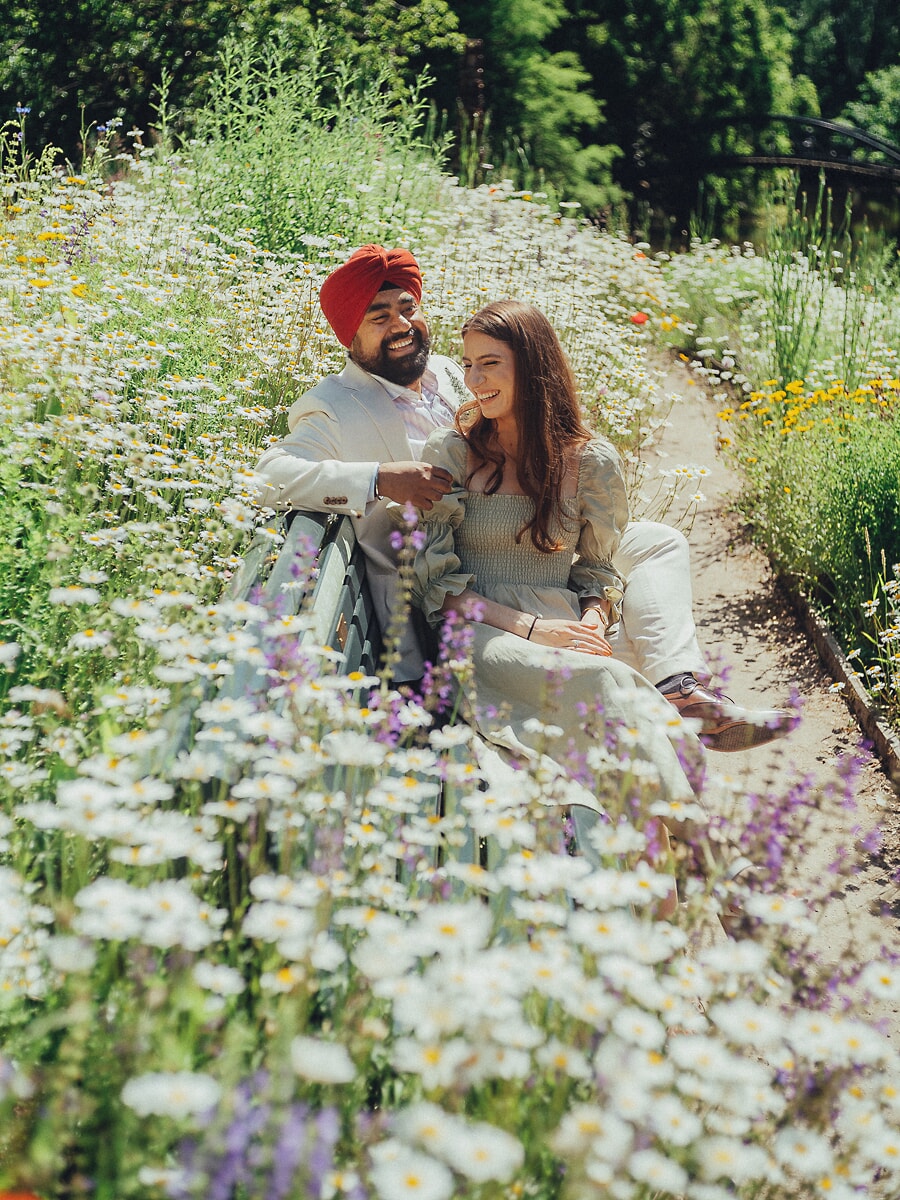 Wedding Ceremony SP16 Sitting close on a bench amid daisies in a sunlit garden, the couple relax for a wedding photographer in Amsterdam