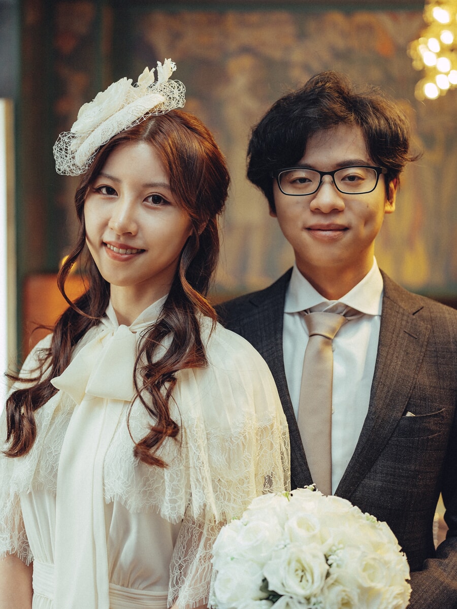 Wedding Ceremony SP18 Vintage-styled newlyweds posing under warm indoor lights, the bride holding a white rose bouquet, a romantic wedding photo session