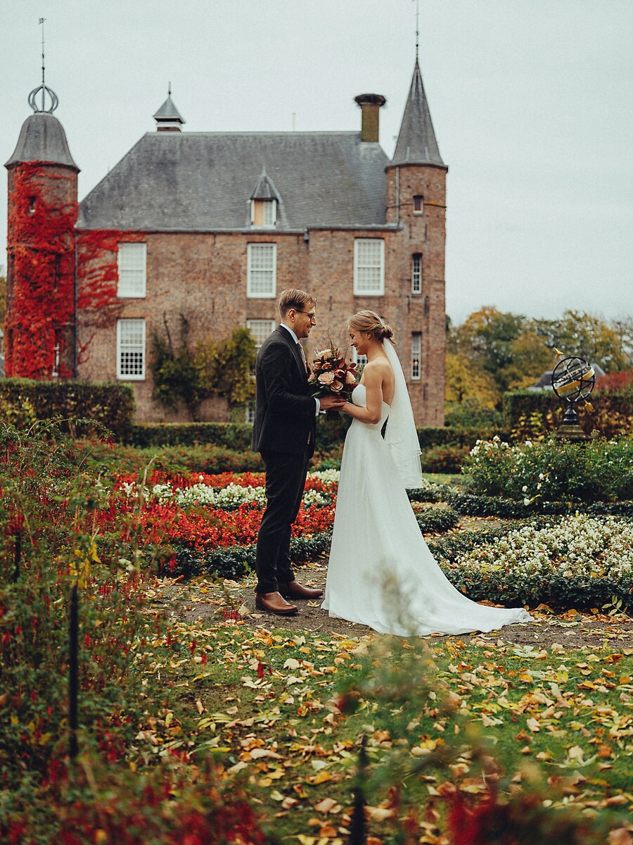 Wedding Ceremony SP20 Bride and groom facing each other before a red-ivy Dutch castle in an autumn garden, captured by a wedding photographer in Amsterdam