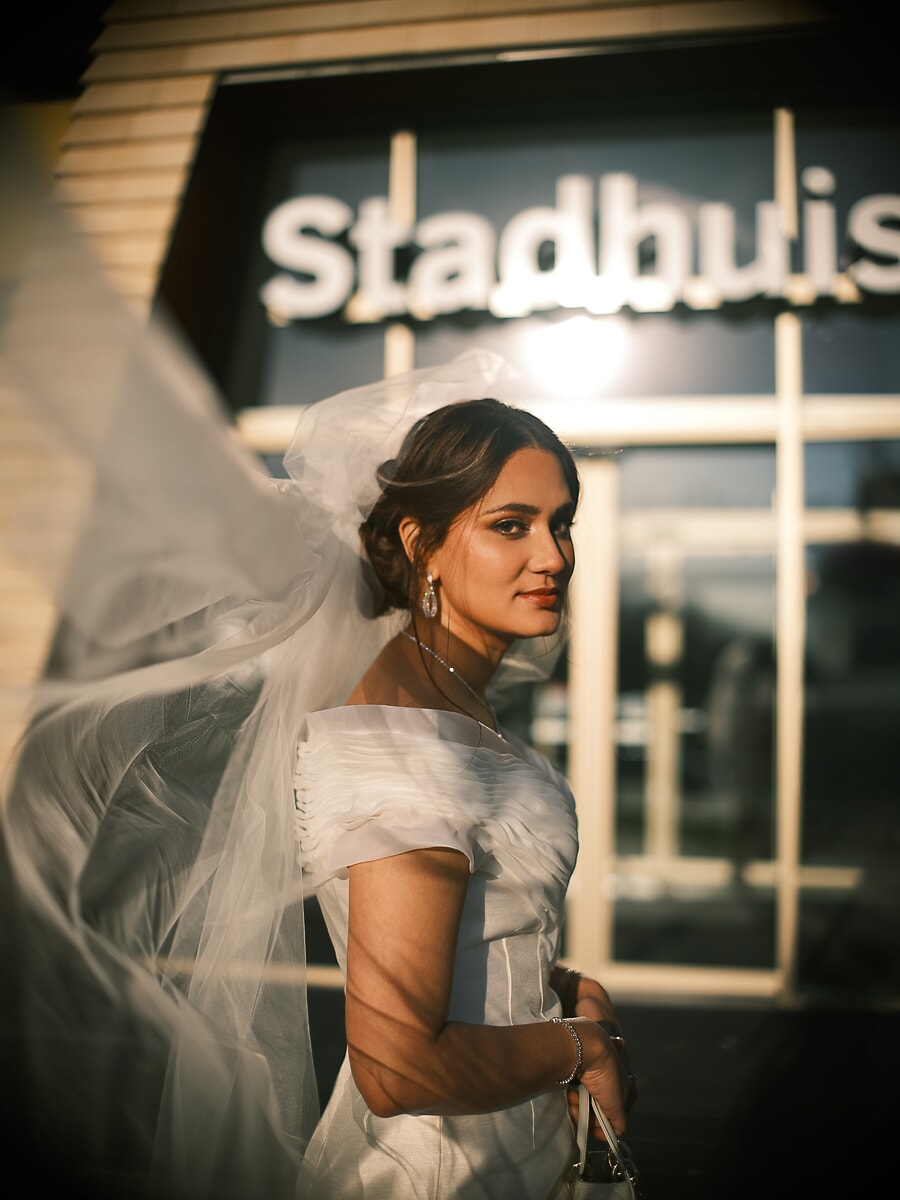 Wedding Ceremony SP3 Veiled bride pausing outside an Amsterdam Stadhuis city hall at golden hour, a cinematic bridal portrait
