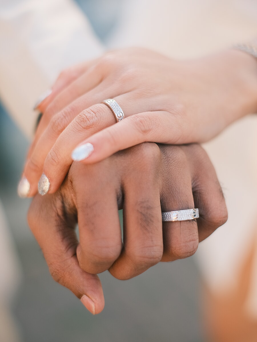 Wedding Ceremony SP5 Close-up of a newlywed couple's hands resting together, their diamond-set rings catching the light in a delicate wedding photo