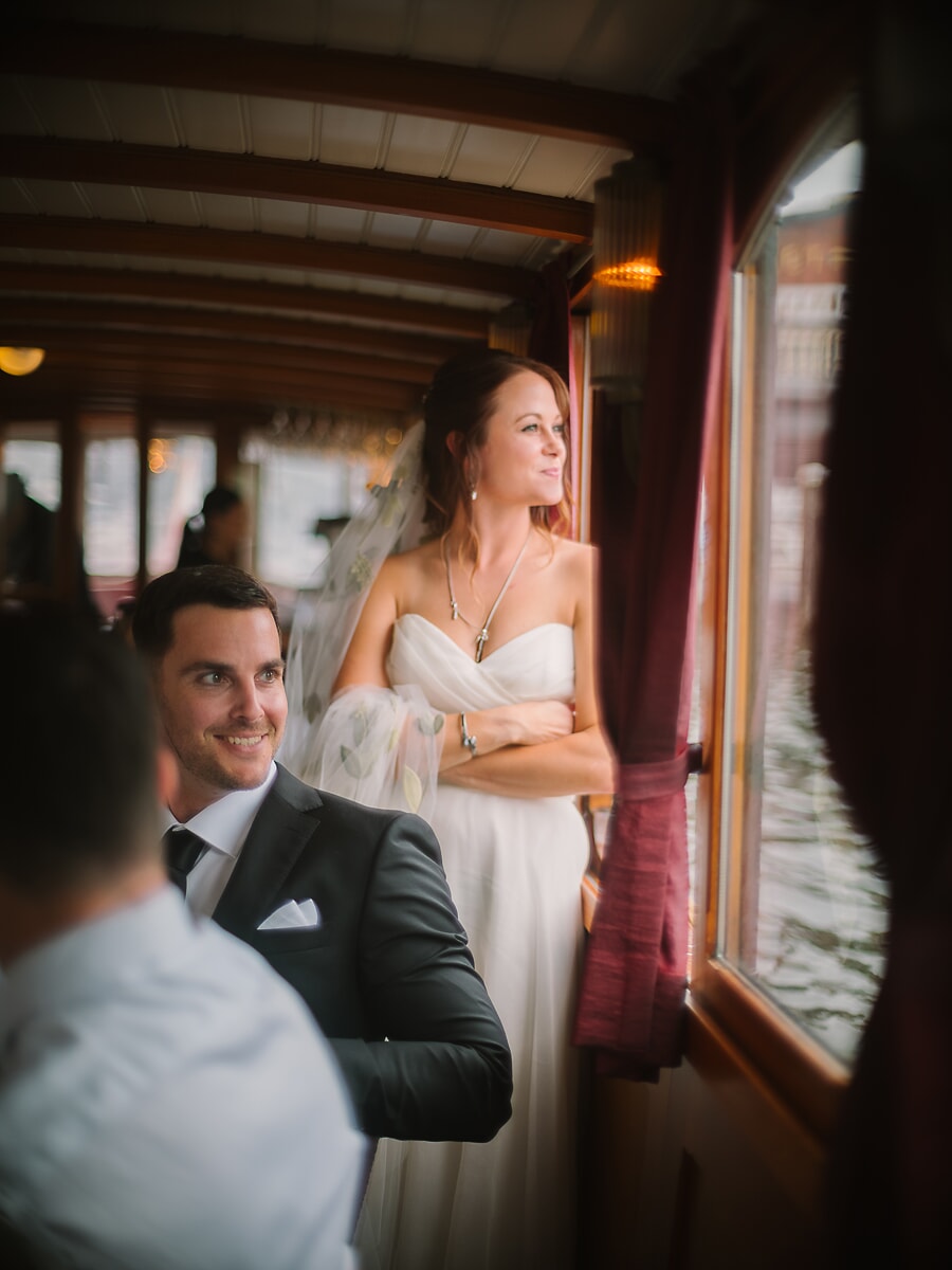 Wedding Ceremony SP6 Bride in a strapless gown gazes from the window of a wooden salon boat, an afloat session with a wedding photographer in Amsterdam