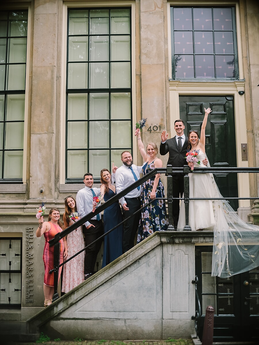 Wedding Ceremony SP8 Wedding party cheer on the steps of a historic canal house, a joyful group moment by a wedding photographer in Amsterdam