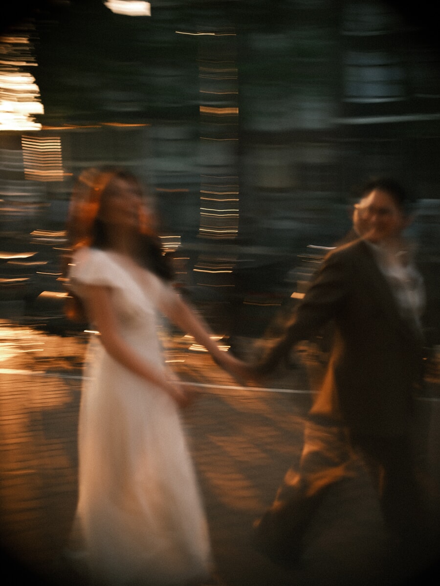 Wedding Bridal SP8 A wedding photographer in Amsterdam blurs the newlyweds as they walk hand in hand through golden city lights