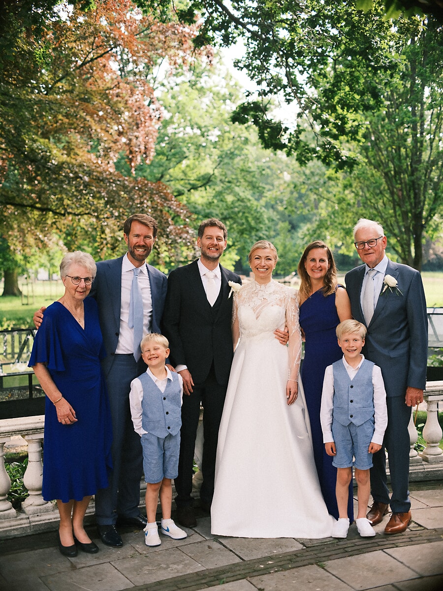 Wedding SP20 Bride and groom pose with parents and two boys in matching blue on a park terrace, a warm family wedding portrait