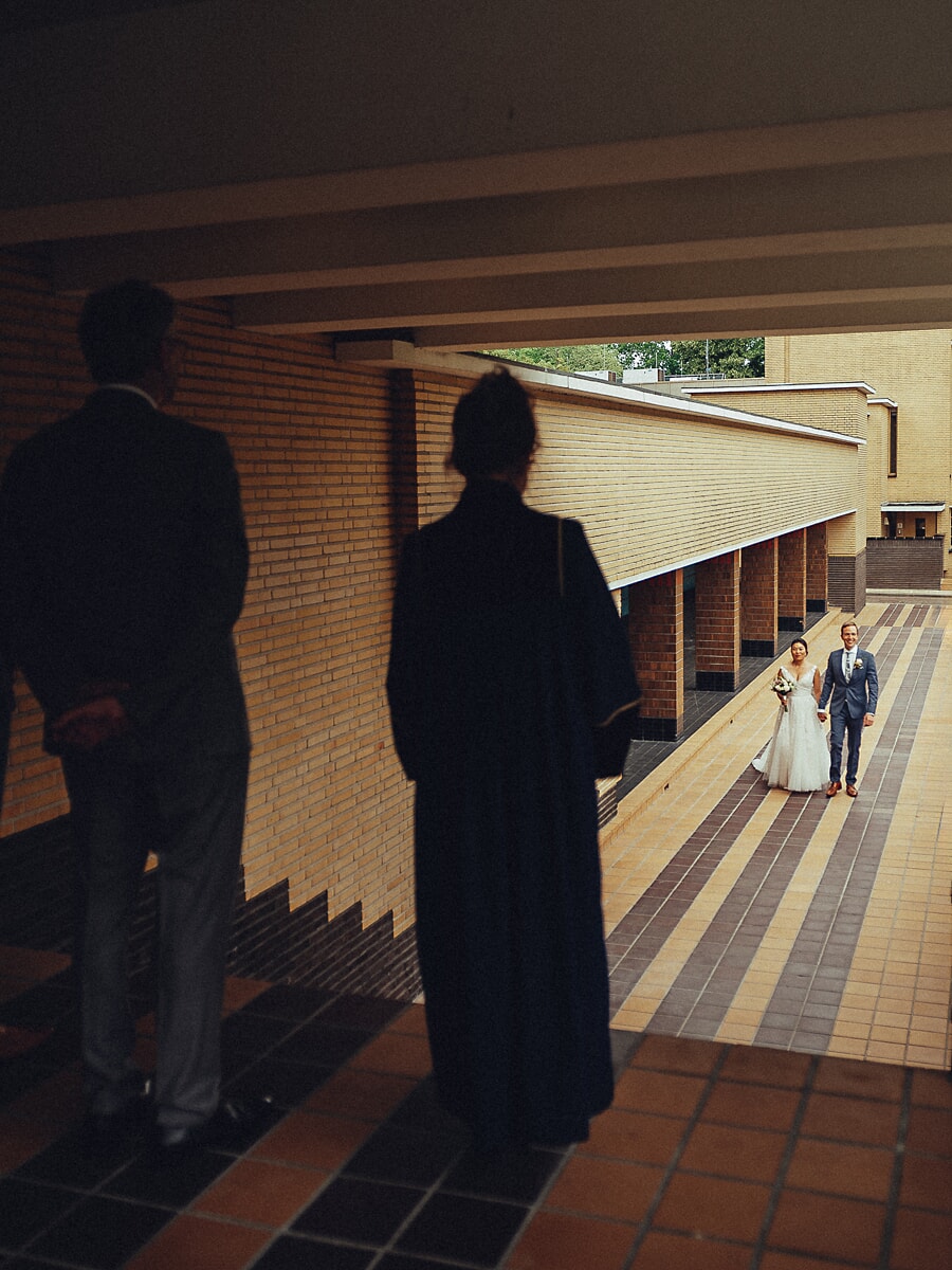 Wedding SP30 A wedding photographer in Amsterdam frames the newlyweds walking a striped brick path between two silhouetted figures