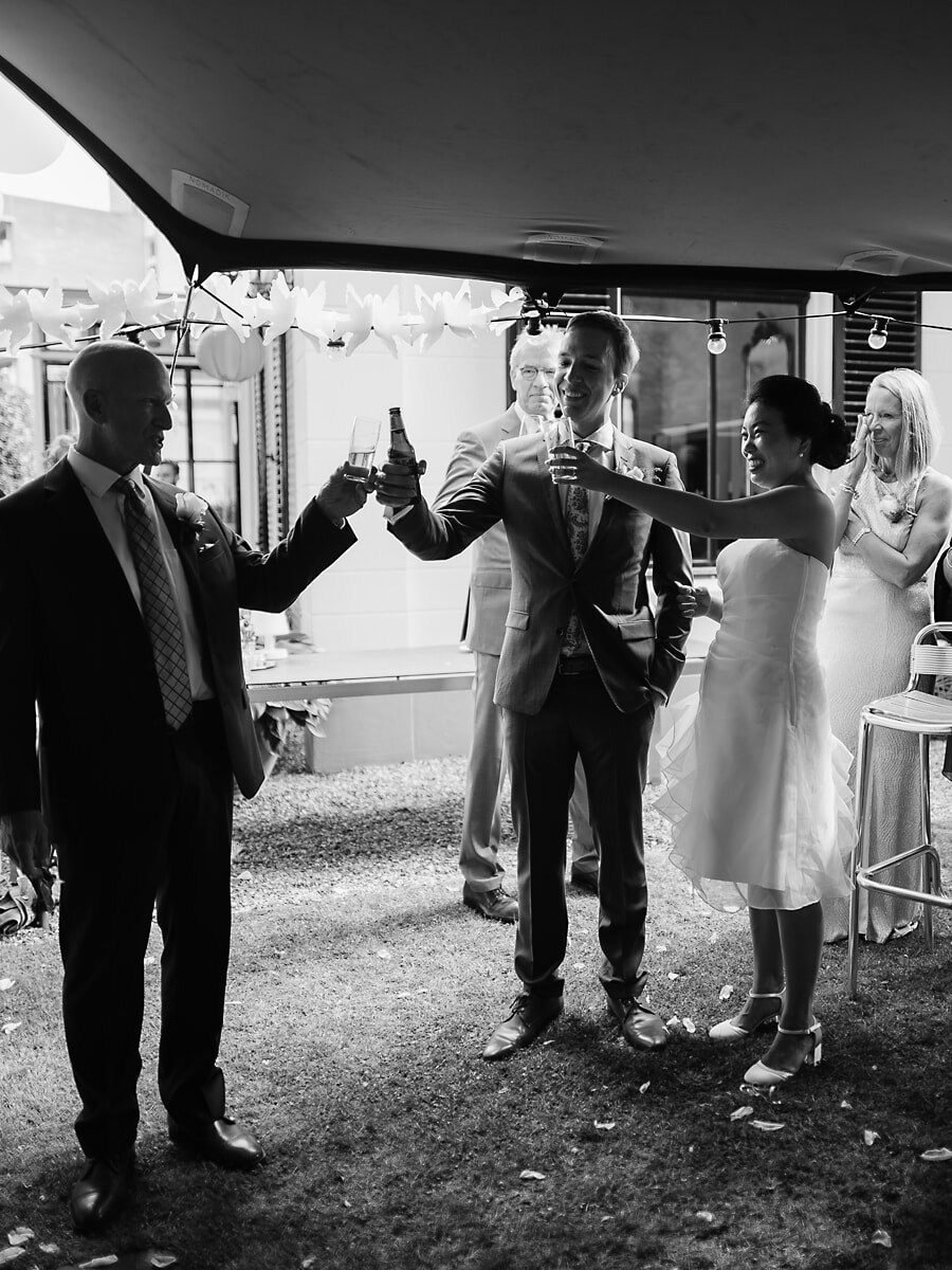 Wedding SP42 A wedding photographer in Amsterdam catches the couple toasting with guests beneath paper lanterns in black and white