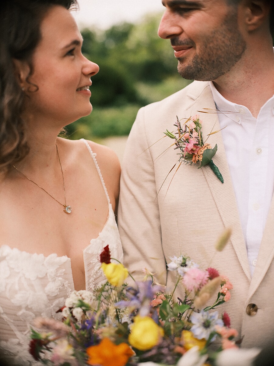 Wedding SP5 Bride and groom face one another in profile, dried flowers on his linen lapel and yellow blooms in her bouquet, an intimate wedding photo