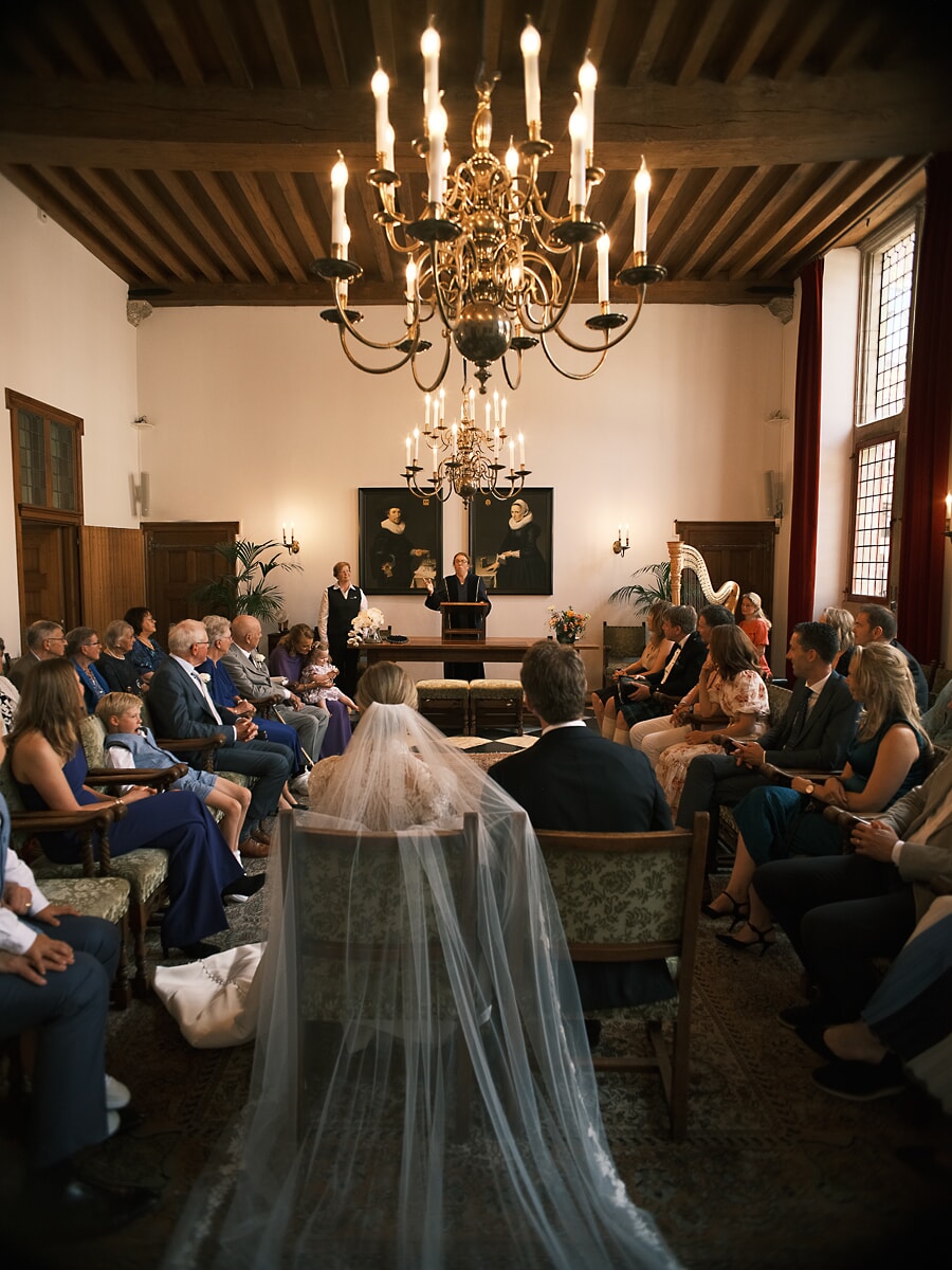 Wedding SP9 Seen past the bride's long veil, the ceremony unfolds under candlelight, an atmospheric photo by a wedding photographer in Amsterdam