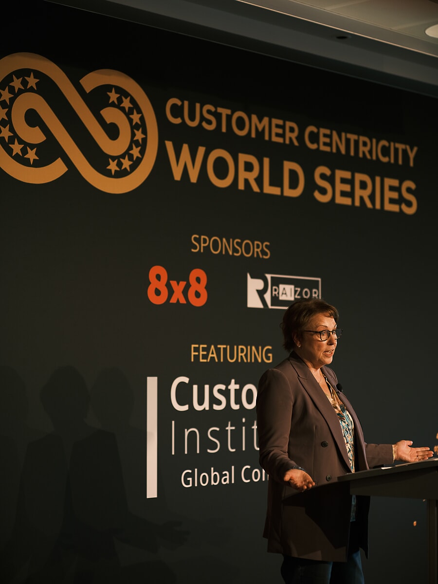 Woman speaking at a lectern in front of a wide conference backdrop