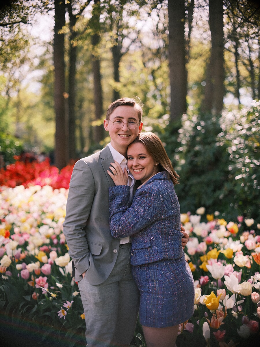 Engaged couple embracing among pastel tulips, her ring hand on his chest during their engagement photoshoot at Keukenhof